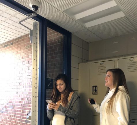 Students Lindsey Gardella, left, and Erin Drew stand beneath one of Tritons new cameras.