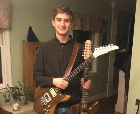 Ethan Tougas with two of his handmade guitars.