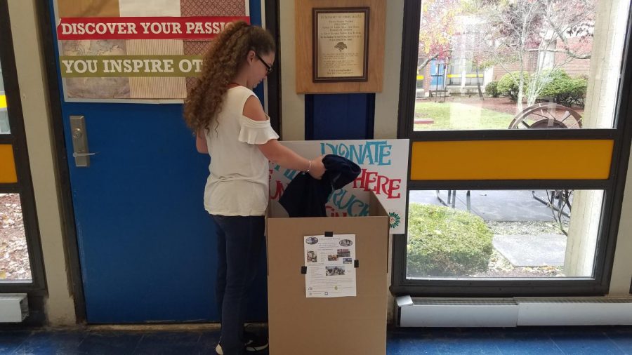 Alexia Miller dropping a jacket into the donation box located in the high school lobby.