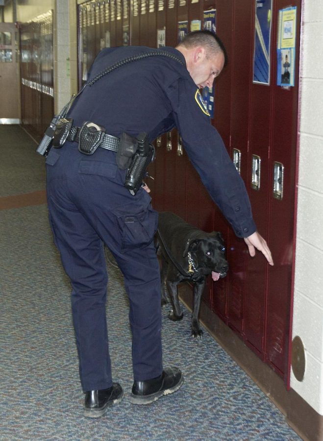 An officer searches lockers with his dog for the scent of narcotics