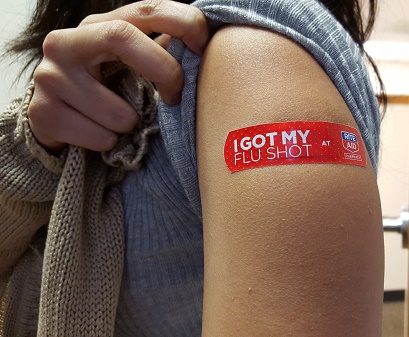 A flu shot recipient shows off their colorful Band-Aid in this advertisement