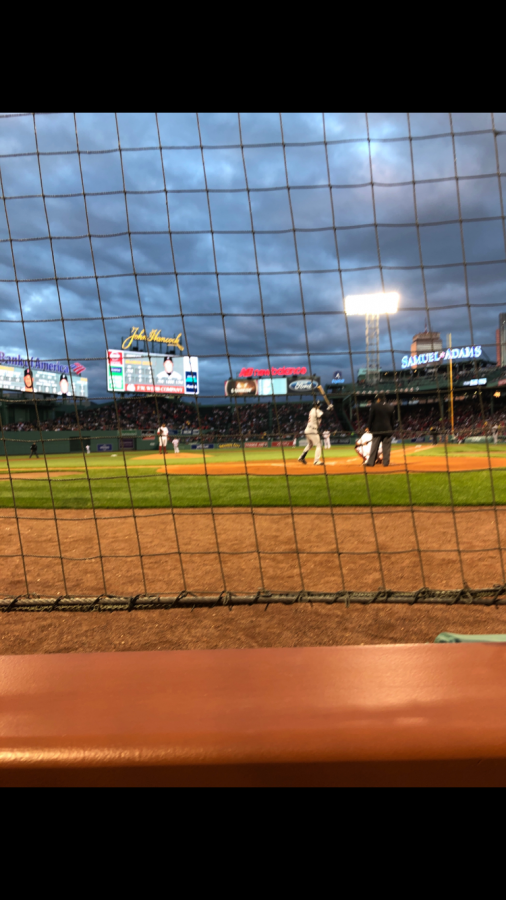 From behind home plate, a fan watches the Red Sox just as the lights come on at Fenway Park.