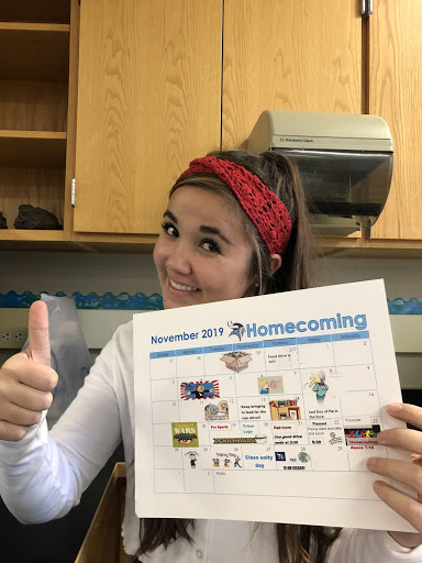 Riley McLaughlin holding the printed schedule for the 2019 homecoming week.