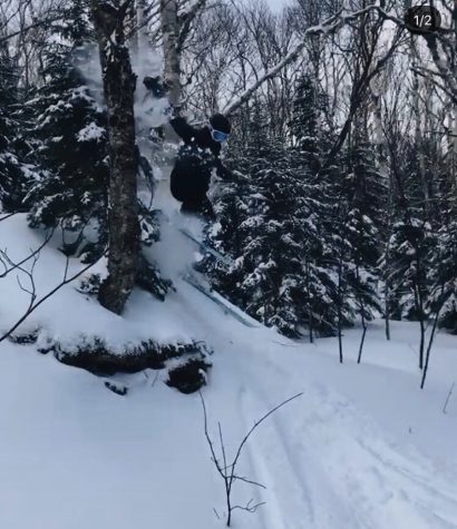 Heidi Ernst pictured in between the sugarbush valley in the backside of the mountain soaring through the trees over a rock at sugarbush resort.