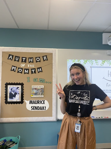 Ms. Gross in her library standing in front of her newly decorated sign.