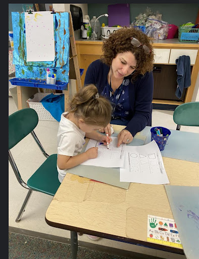 Mrs. Lebreck helping one of her preschool students with their classwork. 