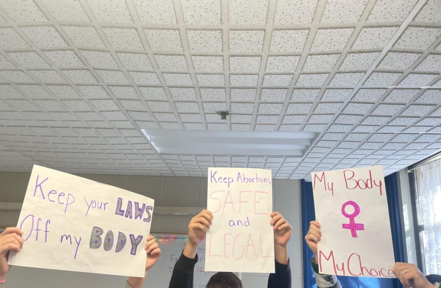 Student-made posters reflect messages often displayed at womens rights demonstrations.