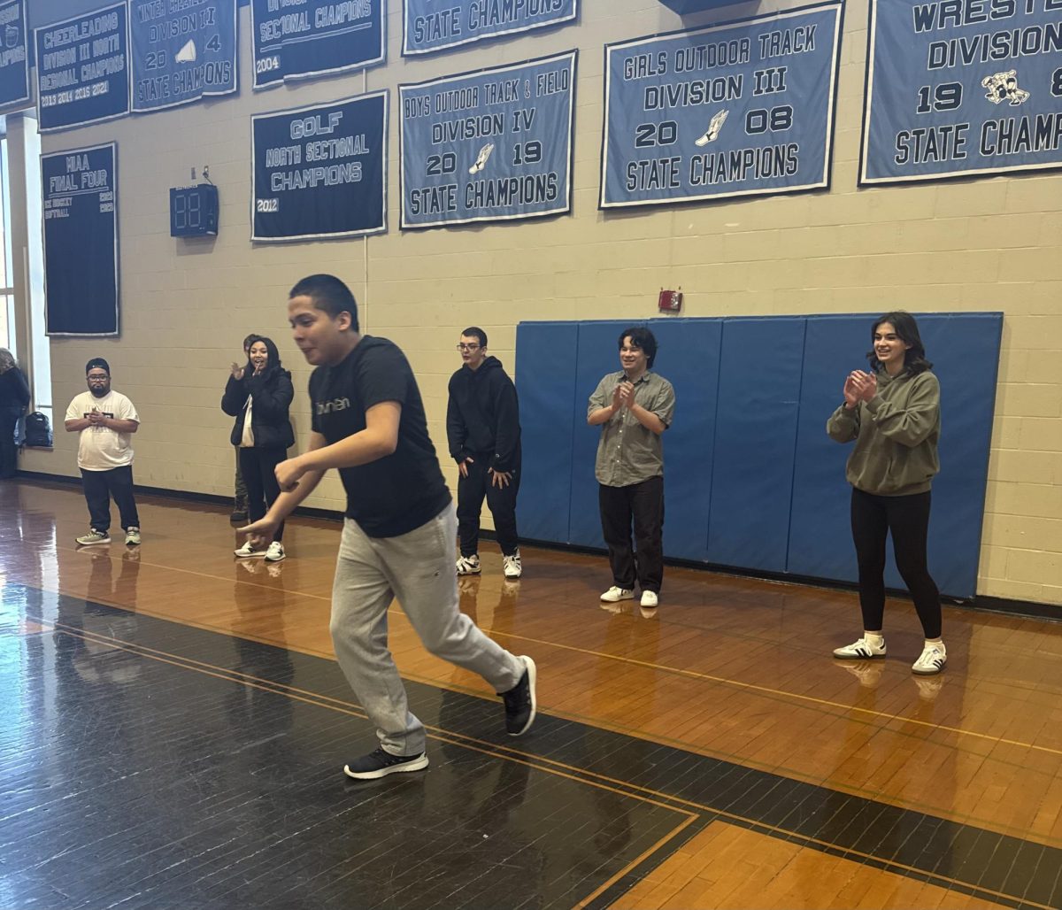 Junior, Oscar Gonzales running up to kick the ball with the support of his classmates behind him