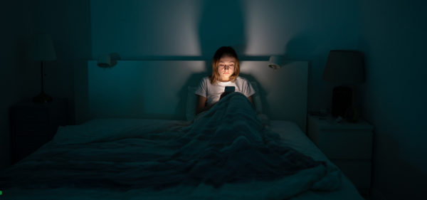 Teen scrolls endlessly through her phone before bed. 