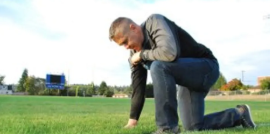 Bremerton High School Football Coach Joe Kennedy prays on the field. 
